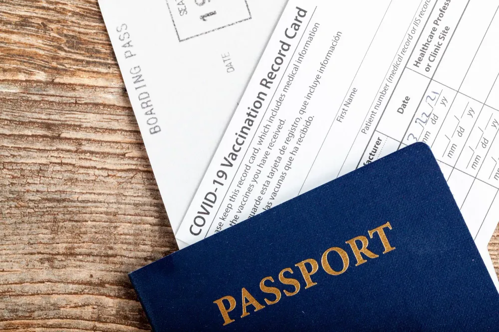 Passport and COVID vaccination card on wooden table